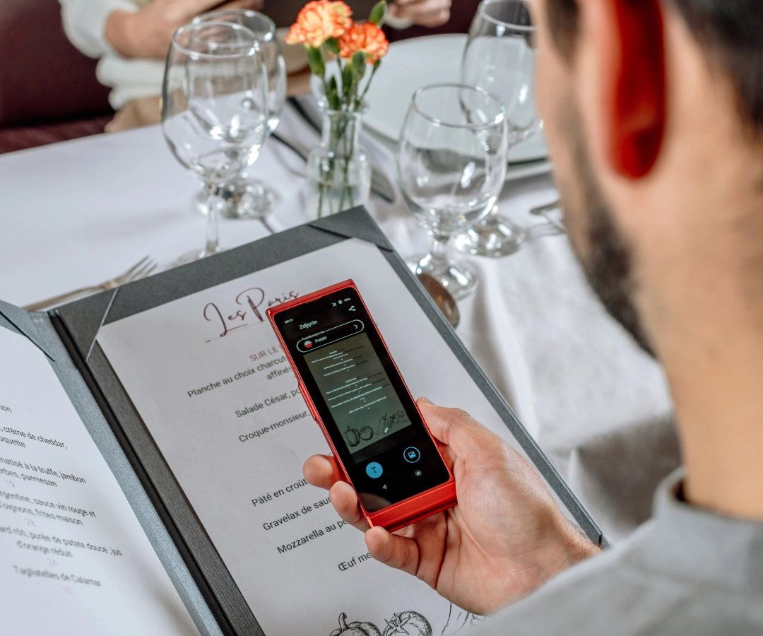 a man in an elegant restaurant translating the menu using a photo translator in an electronic translator