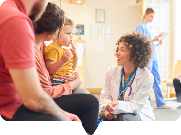 A doctor is explaining something to parents with a young child in a healthcare setting.