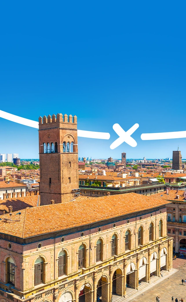 An aerial photograph capturing the historic, red-brick cityscape of Bologna, Italy, under a clear blue sky.